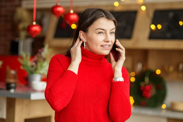 Beautiful woman speaks by a mobile phone. Girl in a red sweater.