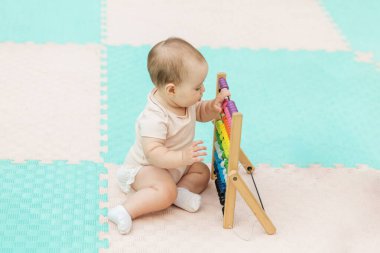 Şirin bebek köpüklü mindere oturur ve ahşap abaküsle oynar. Renkli boncuklar sallanarak sayma ve öğrenme becerilerini geliştirir..