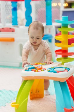 Bebek duruşu ve çocuk aktiviteleri için tasarlanmış renkli, güvenli bir oyun alanında eğitici bir oyuncak masası ile oynamak.