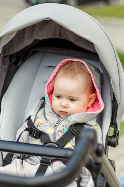 Puantiyeli güzel bir kız bebek. Bebek arabasında oturuyor. Yüzünde ciddi bir ifade var..