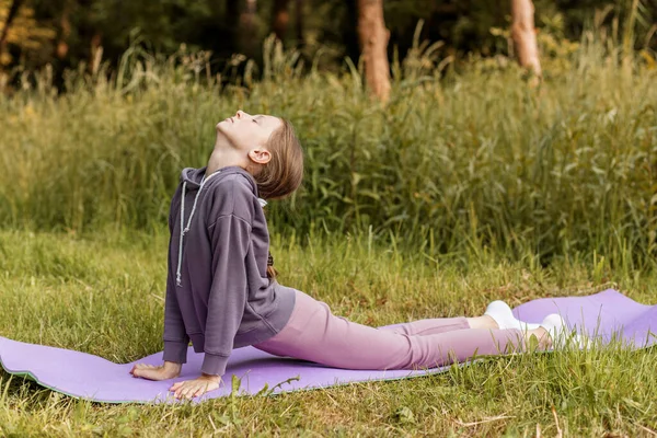 Kobra pozuyla yoga yapan bir çocuk, esnekliği, farkındalığı ve doğada sağlıklı bir yaşam tarzını teşvik ediyor..