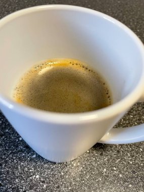 Kahve fincanı ve sıcak kahve mutfaktaki ahşap masada.