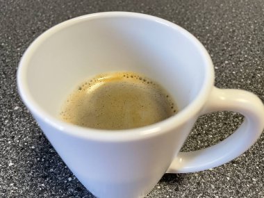 Bir fincan sade kahve ve masada kaşık.