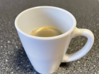 Siyah arka planda köpüklü beyaz bir fincan espresso..