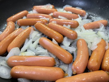 Taze ve lezzetli sosisler tavada.