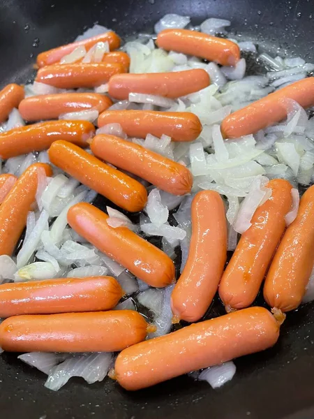 Yakın plan - siyah arka planda büyük beyaz sosisli bir kızartma tavası.