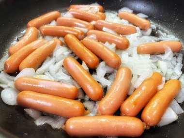 Tavada kızarmış sosis, soğan, et ve yemek. 