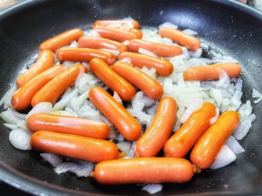 Tavada kızarmış sosis, soğan, et ve yemek. 