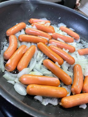 Tavada kızarmış sosis, soğan, et ve yemek. 