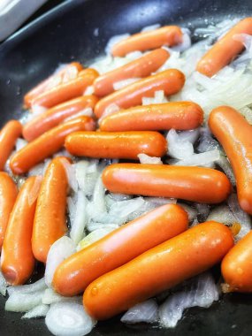 Tavada kızarmış sosis, soğan, et ve yemek. 