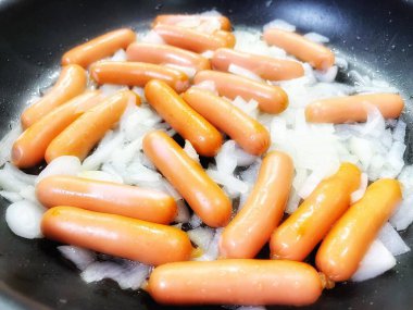 Tavada kızarmış sosis, soğan, et ve yemek. 