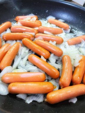 Tavada kızarmış sosis, soğan, et ve yemek. 