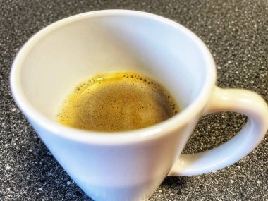 Ahşap masada köpüklü kahve kupası.