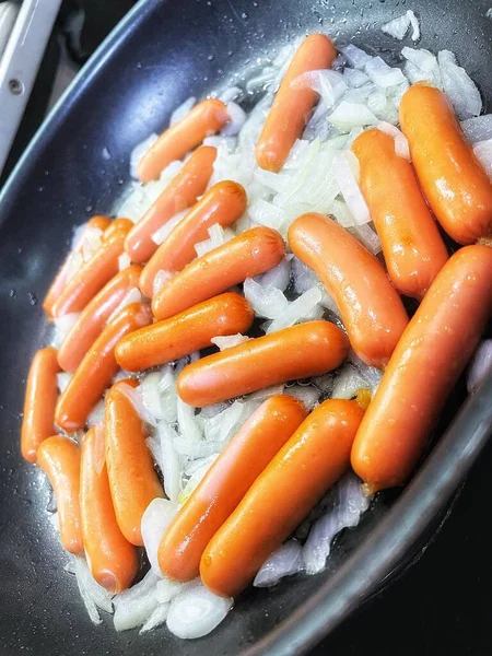 Tavada kızarmış sosis, soğan, et ve yemek. 