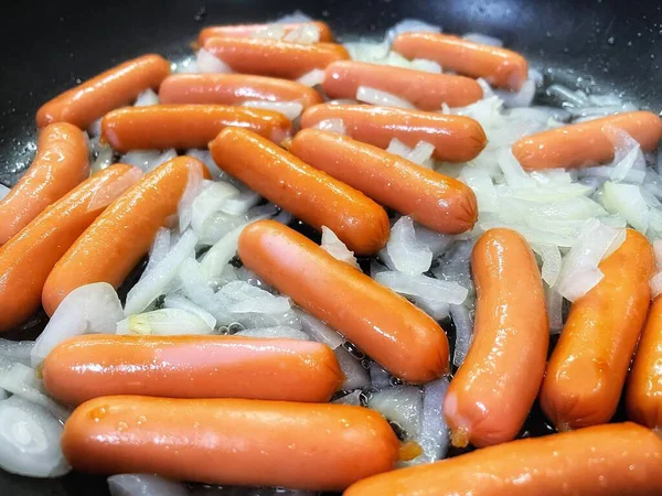 Tavada kızarmış sosis, soğan, et ve yemek. 