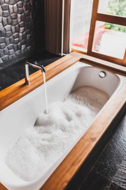Su dolum köpük banyosu. Ahşap kenar ve siyah duvar banyo modern tarzı