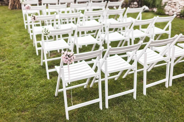 在绿色草地上用木制白色椅子的温馨乡村婚礼仪式 — 图库照片