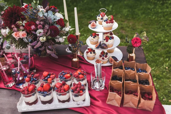新鲜美味的蛋糕与浆果在婚礼接待桌上装饰鲜花 — 图库照片