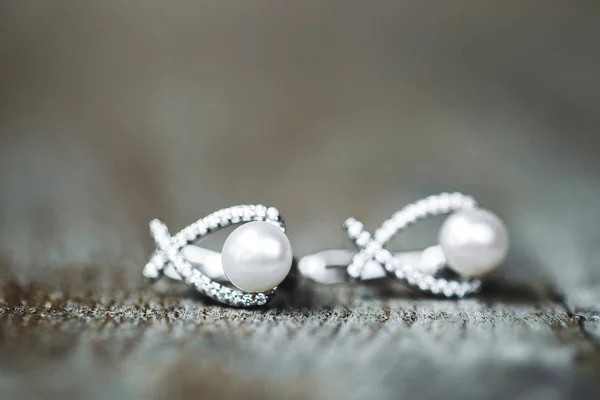 夫妇的女性金色耳环与珍珠和钻石的木质纹理 — 图库照片