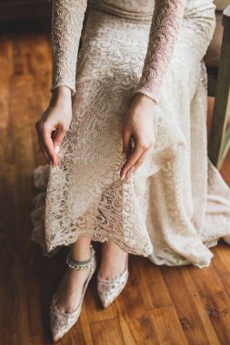 Bride wearing silver metal adornment bracelet on feet, beautiful beige lace dress clipart