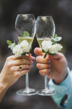 İki şampanya bardağı düğün töreni için çiçeklerle süslenmiş holding eller erkek ve kadın