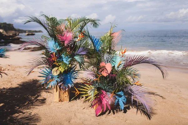 Tropical beach ceremony with painted colorful palm leaves