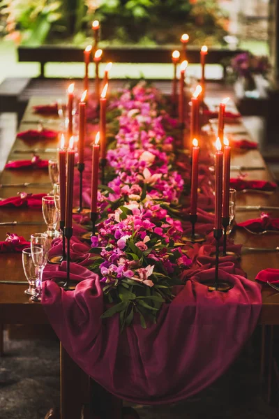 Dřevěná Svatební Stůl Zdobený Červenými Svíčkami Růžové Látky Fialové Orchideje — Stock fotografie