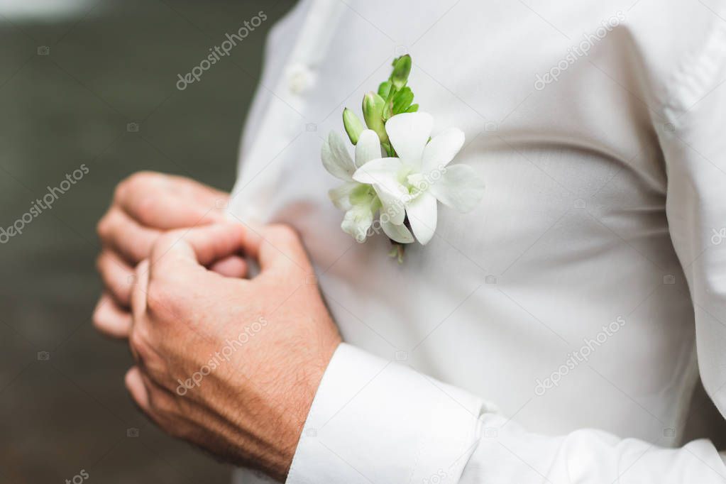 Groom boutonniere with white orchids on white shirt