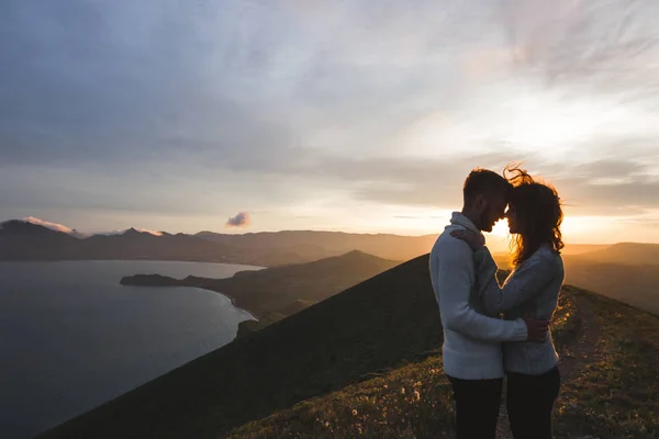 幸福的夫妇拥抱和亲吻在日落与惊人的山景 温暖的傍晚阳光 — 图库照片