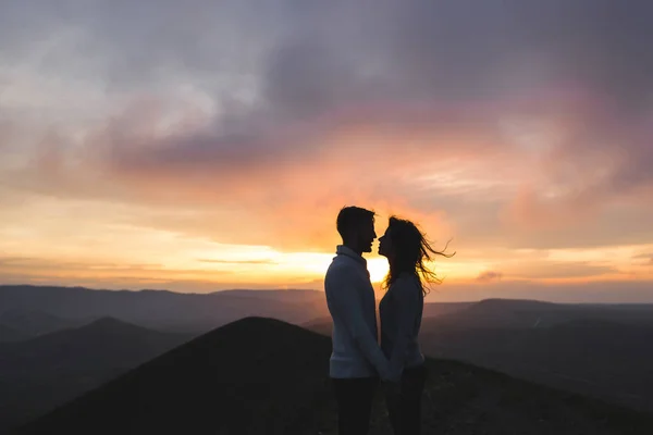 ハグとキスを驚くべき山々 と夕暮れ時の幸せなカップルを表示します 暖かい夜の太陽の光 — ストック写真