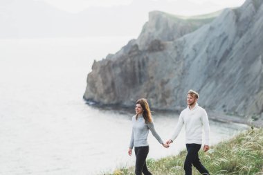 Genç çift dağ manzaralı nordic deniz kıyısında İlkbahar, rahat tarzı giyim kazak ve kot pantolon yürüyüş