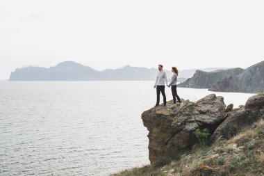 Genç çift dağ manzaralı nordic deniz kıyısında İlkbahar, rahat tarzı giyim kazak ve kot pantolon yürüyüş