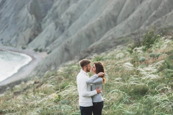 カジュアルなスタイルの服セーターとジーンズ マウンテン ビューと北欧の海岸を歩く若いカップル — ストック写真