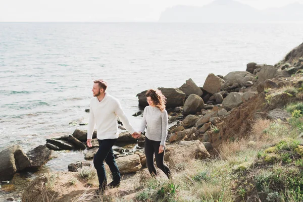 年轻夫妇走在北欧海岸与山景在春天 休闲风格的服装毛衣和牛仔裤 — 图库照片