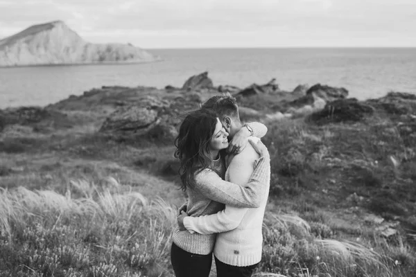 カジュアルなスタイルの服セーターとジーンズ マウンテン ビューと北欧の海岸を歩く若いカップル 黒と白の調子を整える — ストック写真