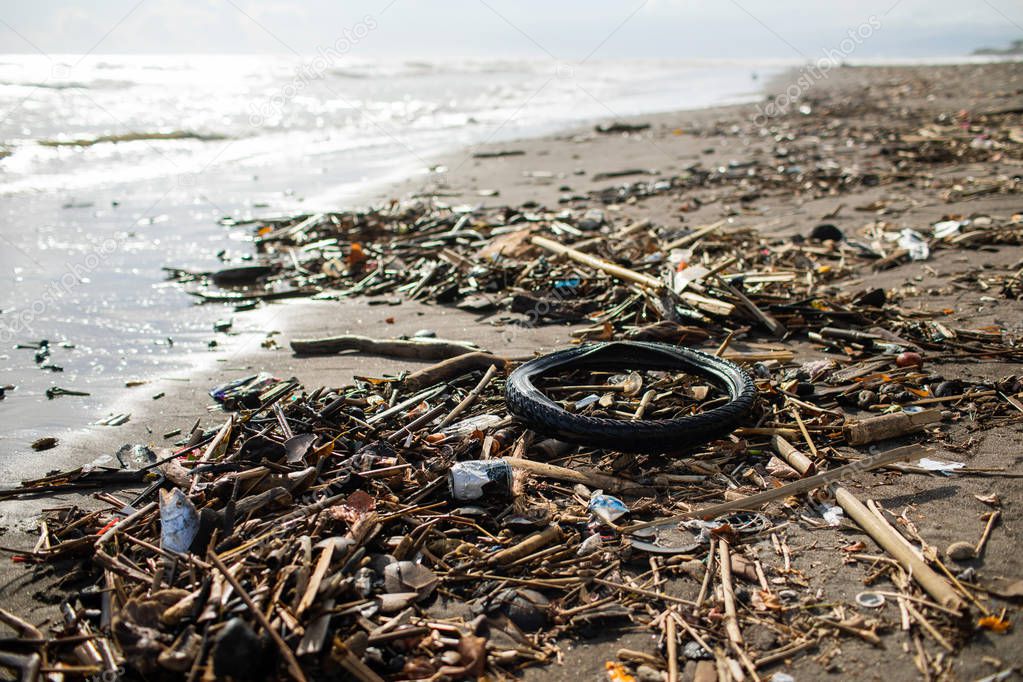 Beach pollution with plastic bottles, rubber tyre and other waste in Bali, Indonesia
