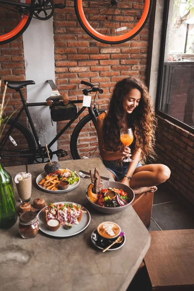 在嬉皮士风格的咖啡馆里享受新鲜有机素食和康布茶一杯自行车设计的妇女 — 图库照片