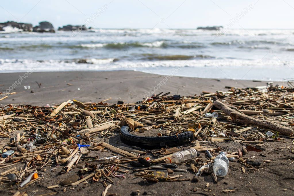 Beach pollution with plastic bottles, rubber tyre and other waste in Bali, Indonesia