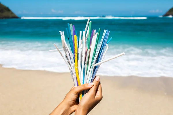 Hand holding heap of used plastic straws on background of clean — Stock Photo, Image