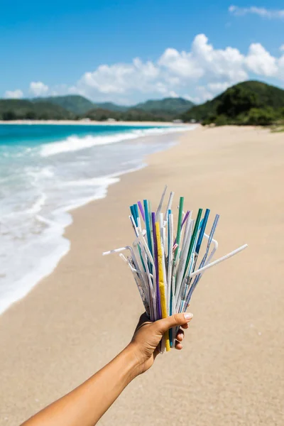 Tangan memegang tumpukan sedotan plastik bekas di latar belakang bersih — Stok Foto