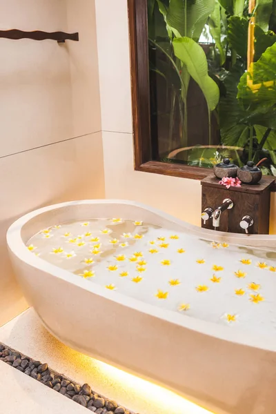 Ванна с пеной и желтыми цветами с тропическим гардом — стоковое фото