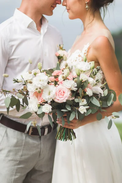Gentle wedding bouquet with lily, pink roses and greens in lovin — Stock Photo, Image