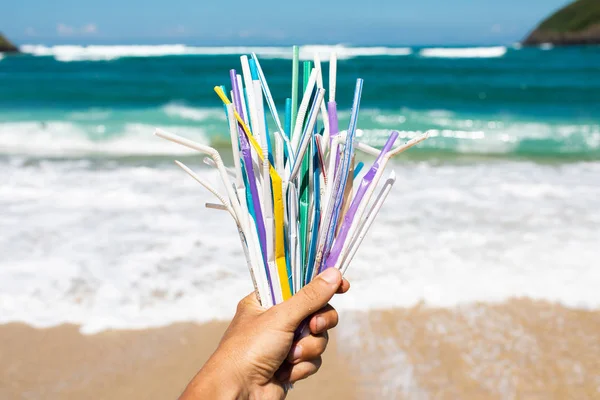 Hand holding heap of used plastic straws on background of clean — Stock Photo, Image