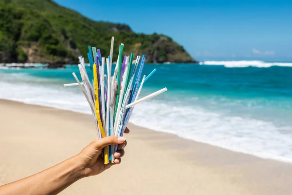 Tangan memegang tumpukan sedotan plastik bekas di latar belakang bersih — Stok Foto