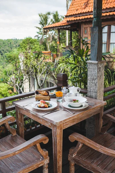 Café da manhã com prato de frutas balinesas, cesta com croissants e — Fotografia de Stock