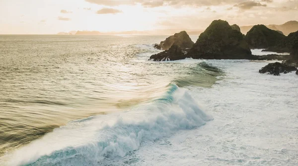 Sunset landscape with huge waves and mountain hills on horizon.