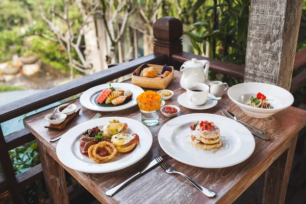 English breakfast with eggs benedict and strawberry pancakes on — Stock Photo, Image