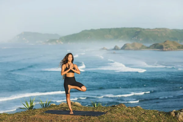 Mujer practicando yoga al aire libre con increíble océano y montaña v —  Fotos de Stock