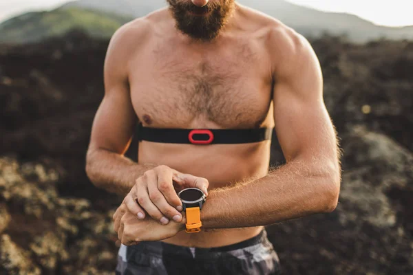 Athletic man watching training results on smart watch or fitness