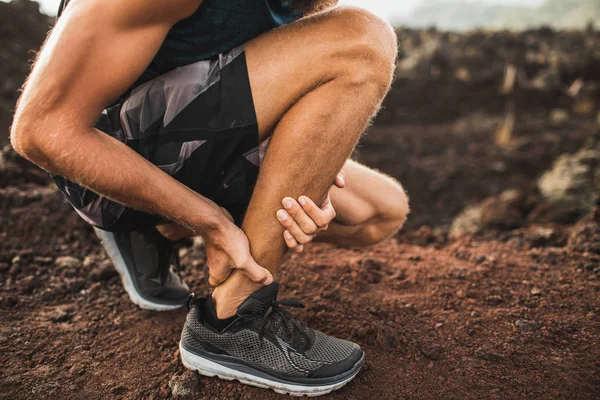 Achilles injury on running outdoors. Man holding Achilles tendon — Stock Photo, Image